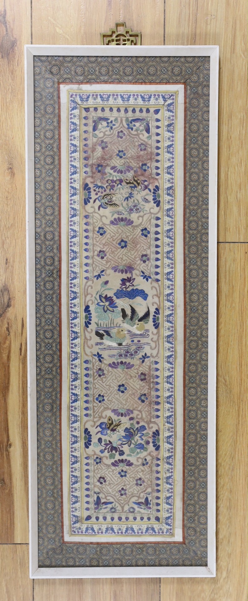 A framed pair of Chinese embroidered sleeve bands using Chinese knot and a another single framed sleeve band, pair 61.5 cms high x 26.5 wide.